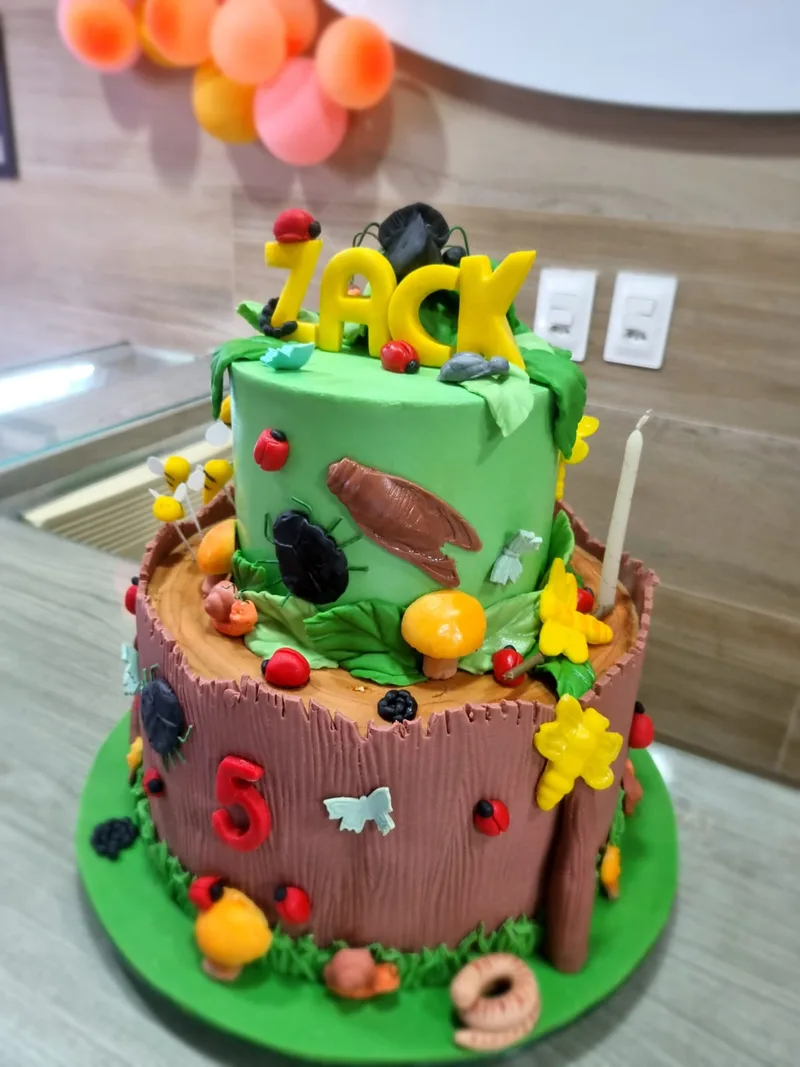 Bolo infantil de dois andares com tema de insetos, tronco, cogumelos, joaninhas e besouros de pasta.