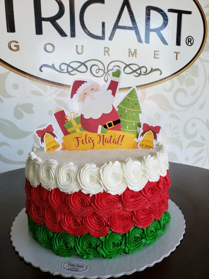 Bolo de Natal coberto de rosetas de chantilly em branco, vermelho e verde, com Papai Noel de papel no topo.