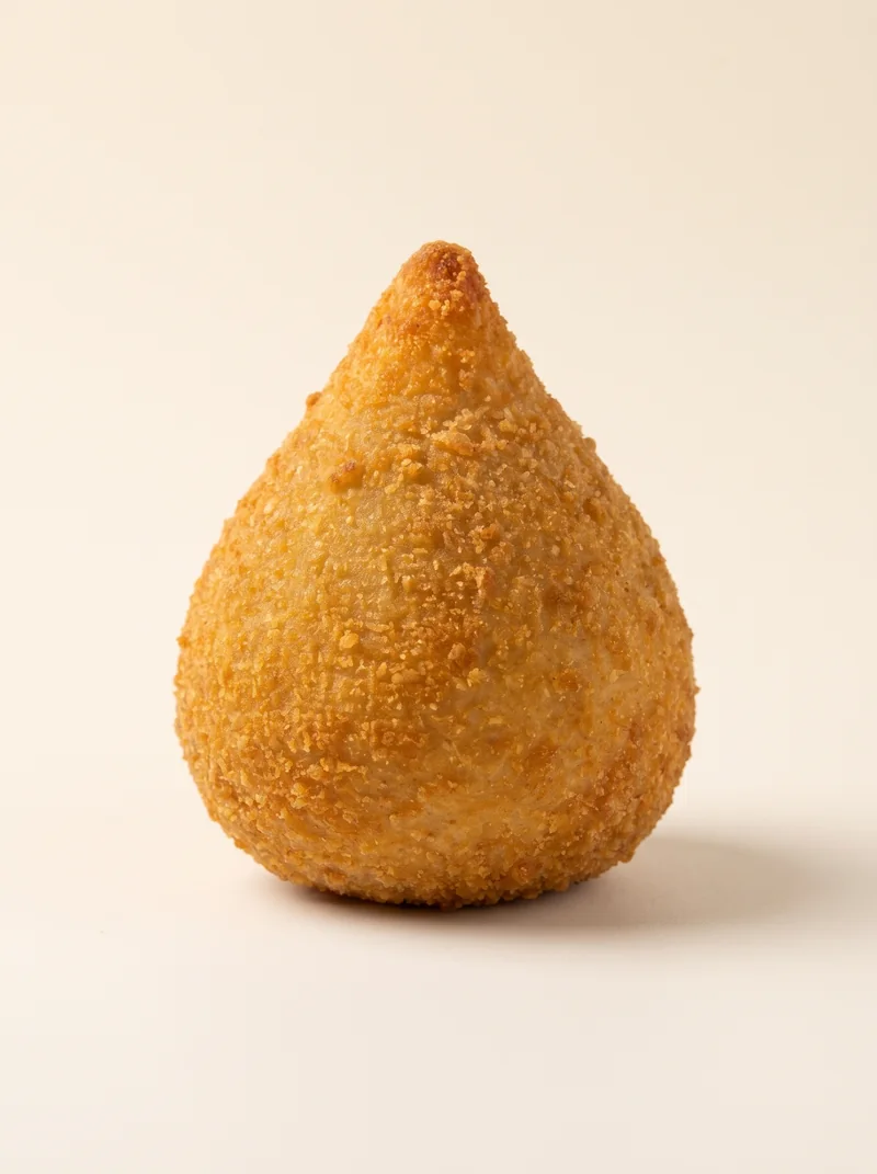 Coxinha inteira sobre fundo creme.